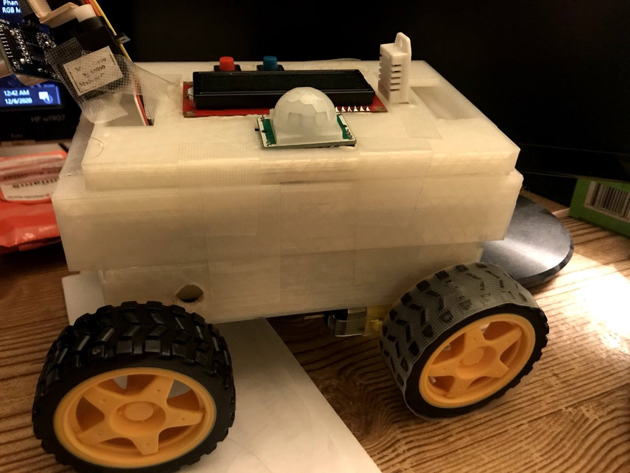 3D-printed autonomous rover prototype with an LCD, sensors, and yellow wheels