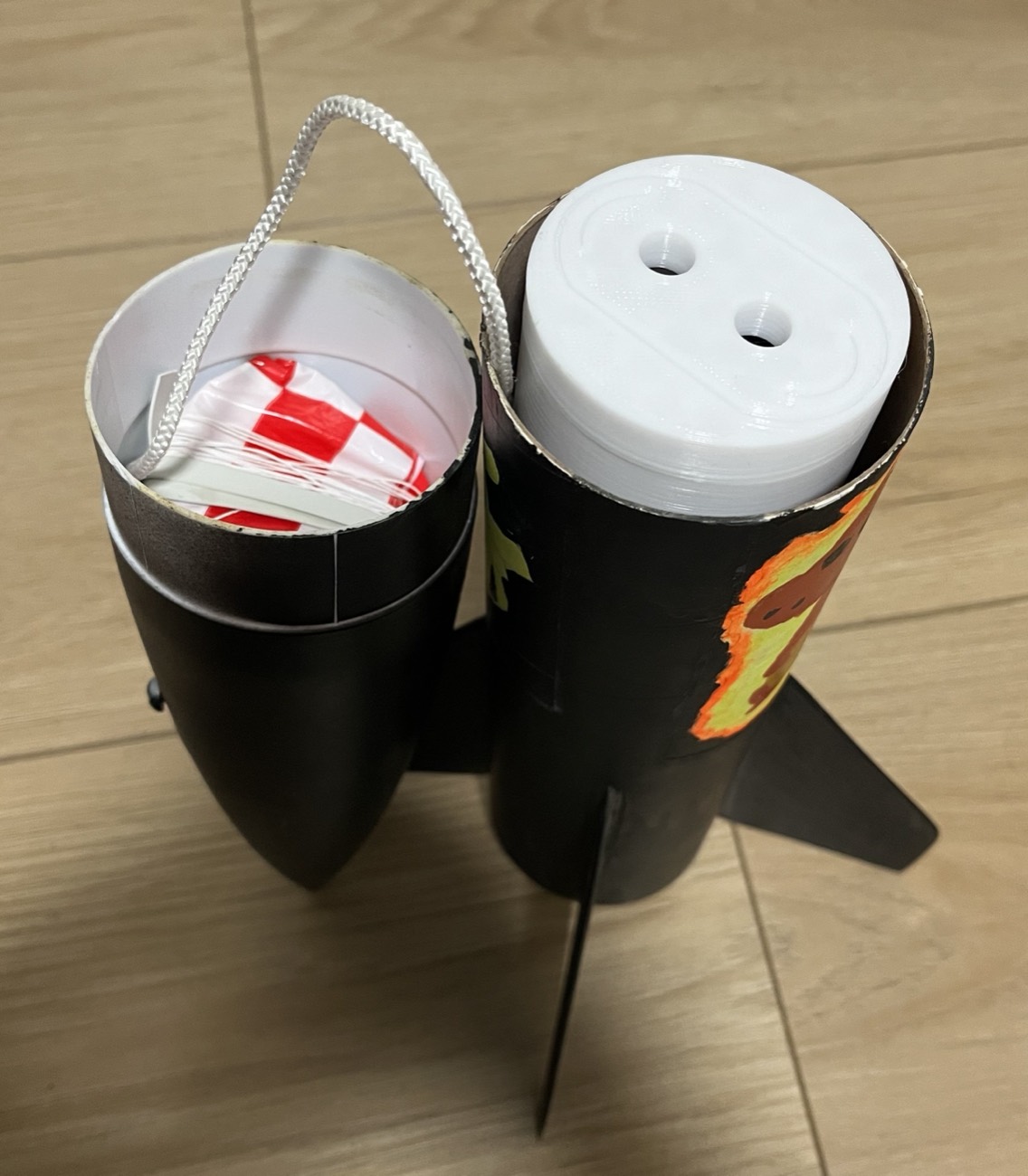 Two sections of a model rocket with the white 3D-printed payload mount visible